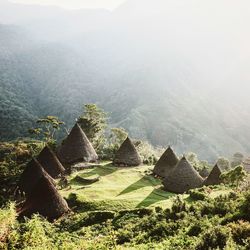 High angle view of thatched roof huts against mountains during foggy weather