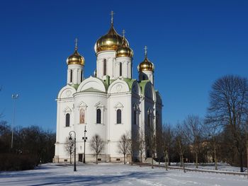 Church by building against clear blue sky during winter