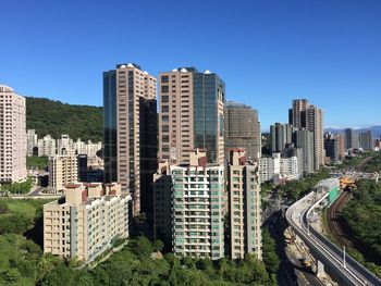 Modern buildings in city against clear blue sky