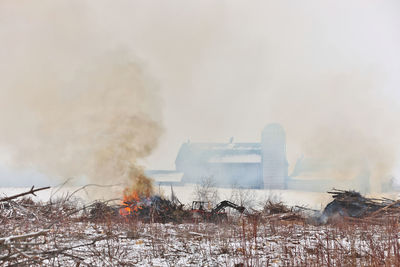 Tractor moves brush during a controlled burn on a farm to make more arable land