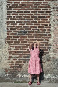 Full length of girl standing against brick wall