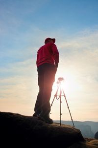 Photographer stay with tripod on cliff and thinking. dreamy orange misty sunrise in beautiful valley