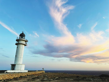 Lighthouse by sea against sky during sunset