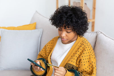 Portrait of young woman using mobile phone at home