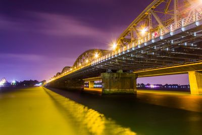 Low angle view of illuminated bridge over river at night