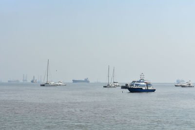 Sailboats sailing in sea against clear sky