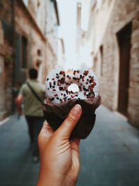 Cropped hand holding donut at street