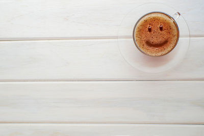 Smile face concept on coffee cream on a white wooden table