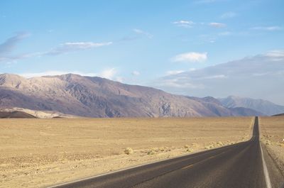 Scenic view of road by mountains against sky