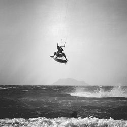 Man kiteboarding over sea against sky