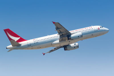 Low angle view of airplane flying against clear blue sky