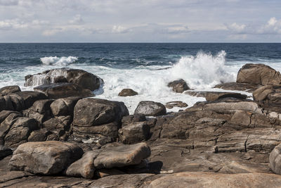 Scenic view of rocks on beach against sky