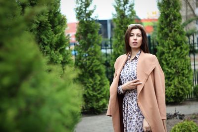 Young woman standing against trees