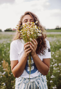 Young woman holding flower in field