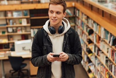 Portrait of smiling young woman standing in library