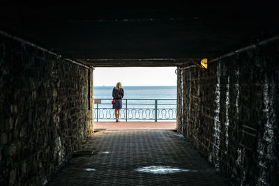 Rear view of woman in tunnel at sea