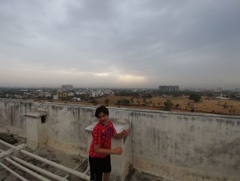Full length of woman standing on railing against sky