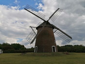 Traditional windmill on field against sky