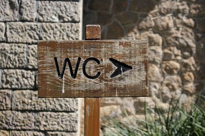 Close-up of wc sign against stone wall