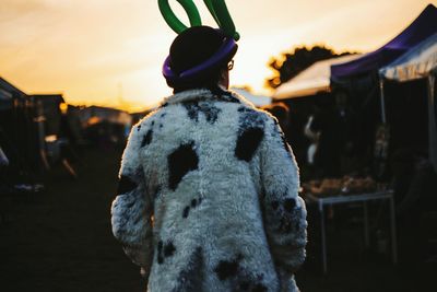Rear view of man wearing fur coat and balloon hat during sunset