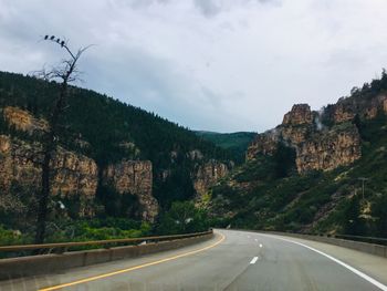 Road by mountains against sky