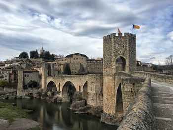 Historical building over canal against cloudy sky