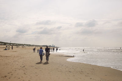 People walking at beach against sky