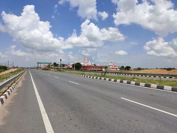 Road by buildings against sky in city