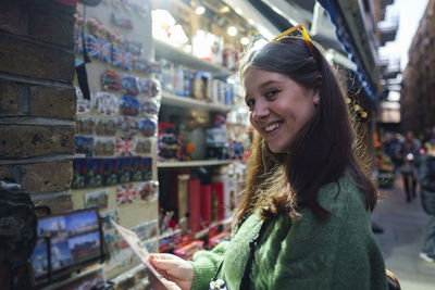Smiling young woman buying souvenirs at store