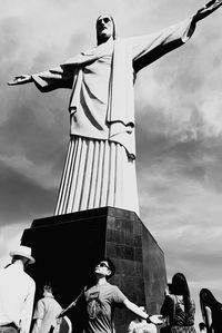 Low angle view of statues against cloudy sky