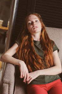 Portrait of young woman sitting on sofa at home