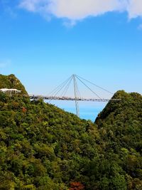 Low angle view of suspension bridge against blue sky