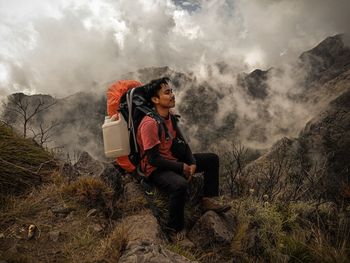 People sitting on mountain against cloudy sky