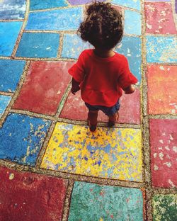 Rear view full length of baby girl walking on colorful floor