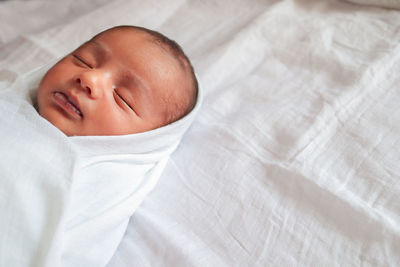 High angle view of baby lying on bed