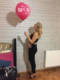 Full length of young woman with balloons at home