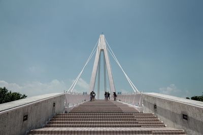 People on footbridge against sky