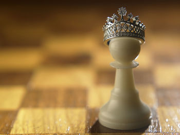 Close-up of crown on pawn at chess board