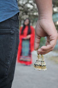 Midsection of man holding earrings by woman