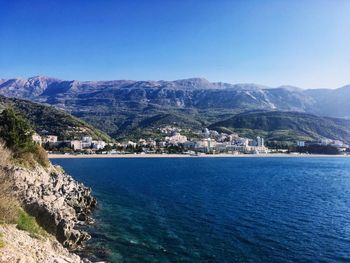 Scenic view of sea and mountains against clear blue sky