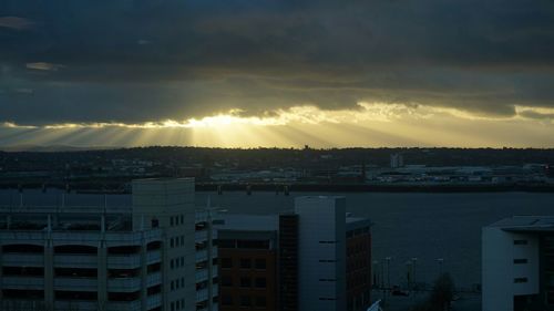 Cityscape against cloudy sky at sunset