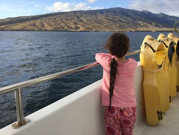 Rear view of girl standing on boat sailing in sea