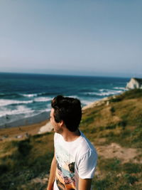 Rear view of man standing on beach against clear sky