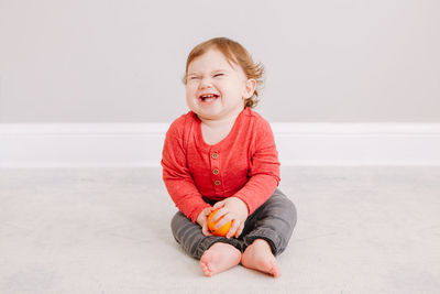 Cute baby boy laughing while sitting on floor at home