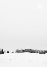 Snow covered field against clear sky