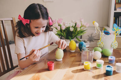 Cute girl with flowers on table at home