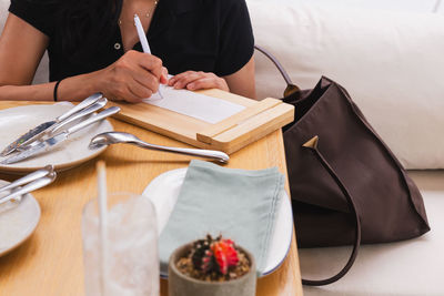 Woman signing slip payment credit card at dinner tale in restaurant.