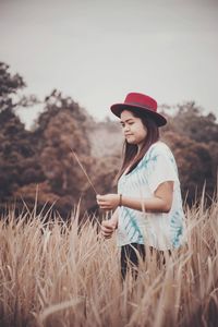 Young woman wearing red hat while standing amidst plants on land