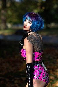 Young woman with pink hair standing on land