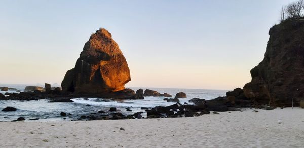 Rocks on beach against clear sky